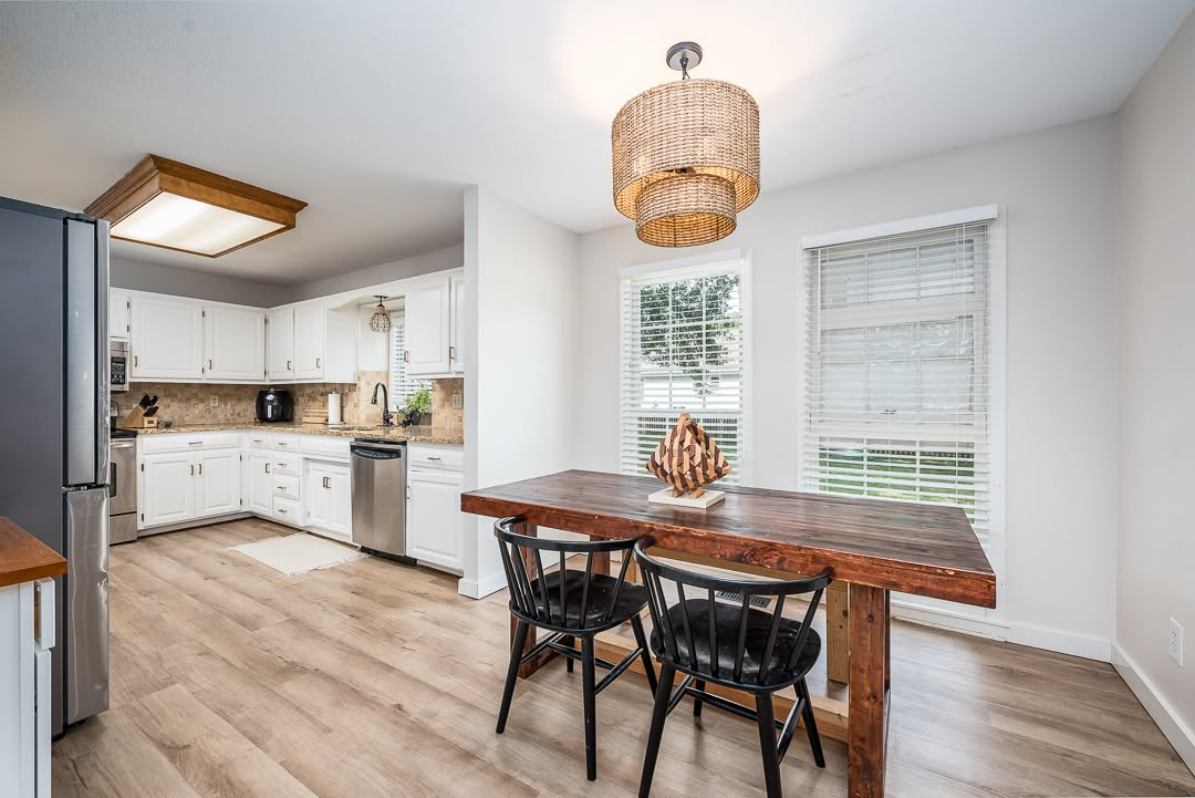 Modern kitchen and dining area with white cabinetry, wood table, and large windows