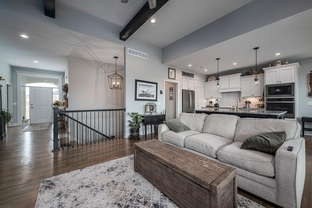 Modern open-concept home with gray sofa, kitchen, staircase, and wood flooring