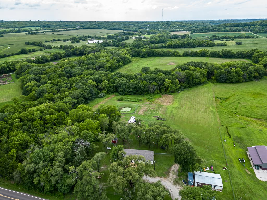 Aerial view of rural farmland with green fields, forests, and scattered buildings