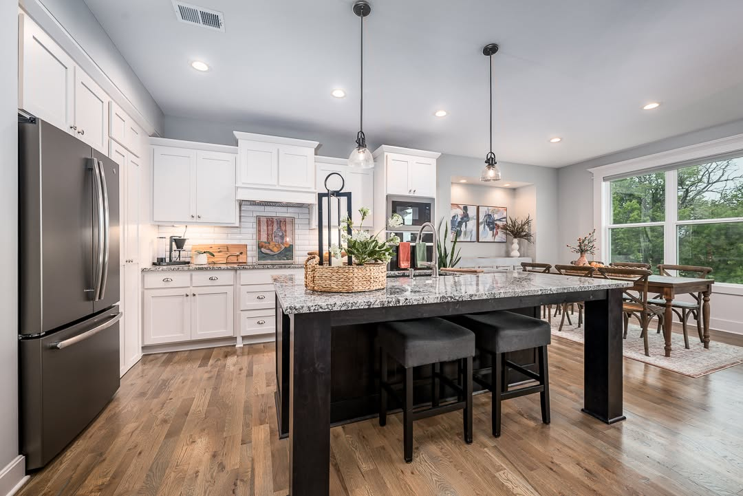 Modern kitchen with white cabinets, granite island, stainless steel appliances, and dining area